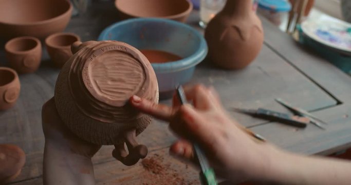 production process of pottery. The potter finally forms and applies textures to the clay kettle. Finishing the bottom of the kettle.