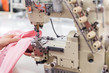 a seamstress working at the sewing machine. textile workshop. closeup