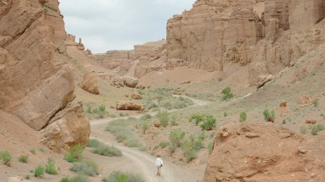 Woman walking down lonely road in desert of Kazakhstan