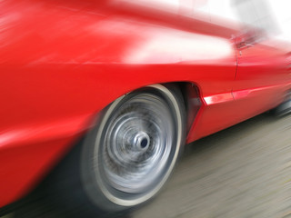 Spinning wheel of a fast riding red muscle car