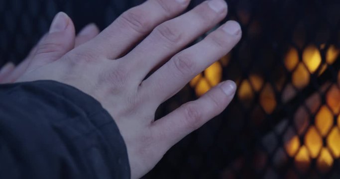 Womans hands in front of outdoor fire during freezing cold winter day - close up
