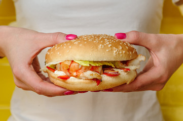 Seafood burger with shrimps holding in young woman hands