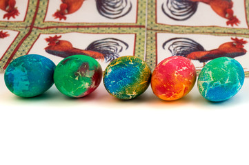 Five painted Easter eggs laid in one row against a paper napkin with a rooster.