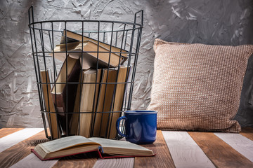Fototapeta na wymiar Old books in a metal basket on a wooden table.