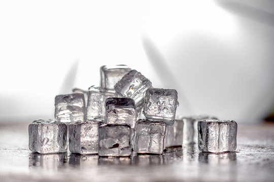Ice cube on wooden table and light blurred background