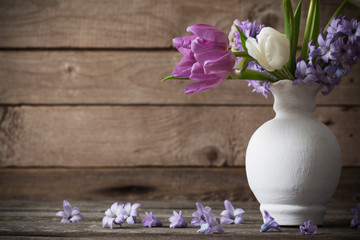 spring flowers in vase on old wooden background