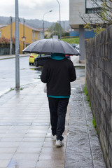 man in sports suit with umbrella outdoors, rear view
