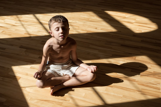 Charming little boy is while doing yoga at home
