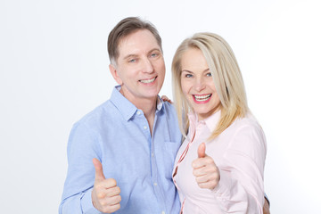 Happy middle aged couple in embraces and show thumb up.