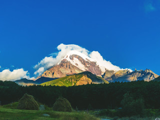 Travel, adventure background. The summit of mount Kazbek in the cloud at sunrise. Georgia