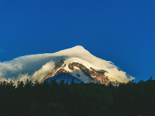 Travel, adventure background. The summit of mount Kazbek in the cloud at sunrise. Georgia