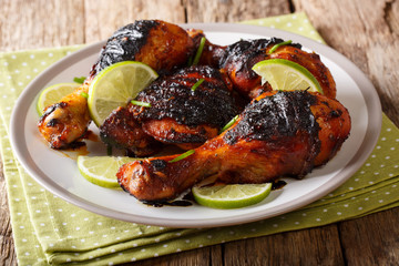 Hot spicy grilled chicken drumstick with lime and green onion close-up on a plate on a table. horizontal
