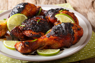 Caribbean grilled chicken drumstick with lime and onions closeup on a plate on a table. horizontal