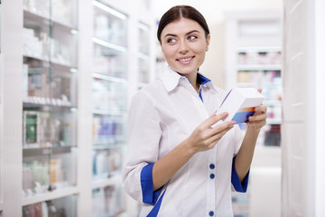 Interesting fact. Appealing female pharmacist staring aside while carrying medication