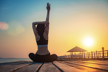 young woman sport exercise with yoga practice on wooden bridge in the sea at sunset, relax and comfortable in place