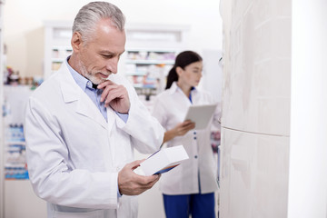 Obraz premium People health. Reflective male pharmacist touching face while working with medical production