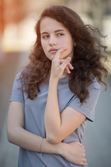 Portrait of a young caucasian woman. Happy beautiful curly girl close-up, wind fluttering hair. Spring portrait outdoors.