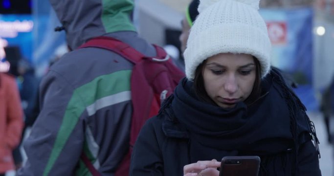 Womans uses smart phone outdoors in winter at outdoor festival