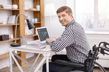 Doing analytics. Attractive man typing article while looking at camera