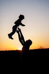 Silhouette of a man and his son playing together outdoor at sunset. Vertical photo. Family concept