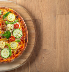 Fresh backed pizza with vegetables on a wooden board .