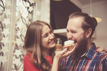 Love and friendship concept. Young beautiful and happy Caucasian couple hugging while having good time together indoors. Handsome man with thick stylish beard embracing his girlfriend