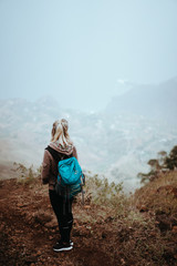 Fototapeta premium Female hiker looking down over a vertiginous misty ridge on the route to Coculi. Santo Antao Cape Verde