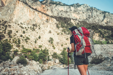 Hiking in the mountains. A girl stands against the background of high mountains. The girl is resting.