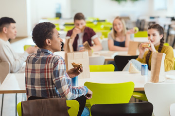 group of high school students chatting while taking lunch at school cafeteria