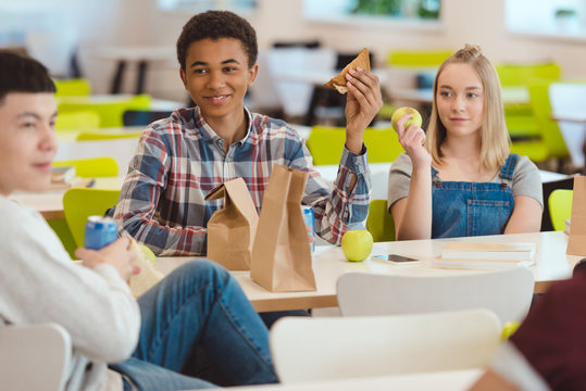 multiethnic group of high school students chatting while taking lunch at school cafeteria