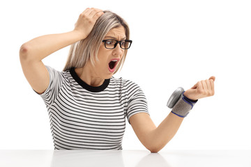 Shocked young woman sitting at a table and measuring her blood pressure