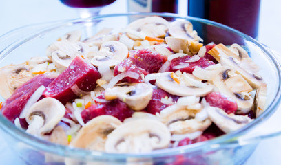 Preparation of beef with mushrooms and onions. Raw meat. Red wine and glassware