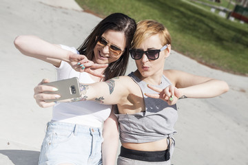 Two natural looking young best friends girls making a selfie photo with smartfone