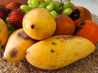 Yellow papaya persimmon fruit and grapes lie on the tray