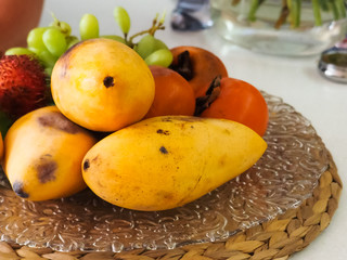 Yellow papaya persimmon fruit and grapes lie on the tray