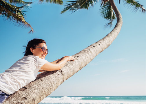 Carefree time summer vacation. Smiling woman lies on the palm tree