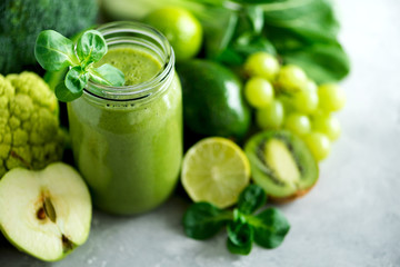Glass jar mugs with green health smoothie, kale leaves, lime, apple, kiwi, grapes, banana, avocado, lettuce. Copy space. Raw, vegan, vegetarian, alkaline food concept. Banner