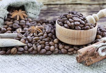 Grain coffee in a wooden cup and burlap. Cinnamon sticks are tied with string. Anise and dried slices of lemon on an old wooden board.