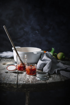 Jars filled with red oranges jam on a rustic wooden table