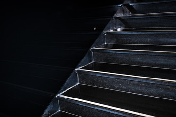 Black granite staircase going diagonally upward reflecting in black wall with copy space.
