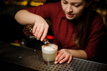 Fototapeta na wymiar Female bartender making a final preparing for serving a delicious white cocktail