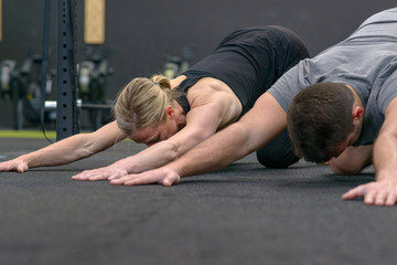 Naklejka premium Man and woman stretching in a gym