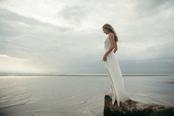 Fototapeta na wymiar Girl in white dress on sea beach 