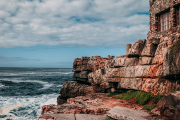 Side view of an old derelict stone building overlooking the ocean along the coast of Hermanus,...