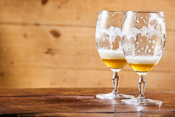 Two emptied glasses of beer on a counter