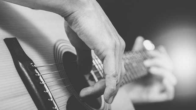 male musician playing acoustic guitar, black and white