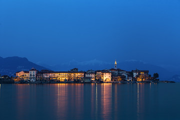 Fototapeta premium Reflections on the water by the lake at sunset. Fisherman Island, Lake Maggiore, Italy.