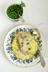 Rabbit in sour cream sauce with tender mashed potatoes and green peas. Rustic style.