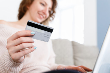 Close up shot of caucasian womans hands holding credit card, using laptop fop paying online or for paying bills