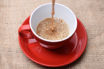 Coffee making concept. Red ceramic mug pouring, filling with coffee,